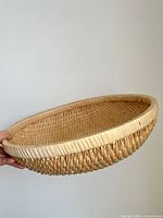 Full view of round rattan basket held sideways showing profile and rim