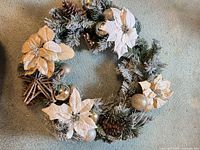 Full view of frosted evergreen wreath with ornaments, poinsettias and pine cones