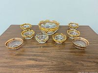 Full set of nine clear glass bowls arranged on table showing sizes and gold trim
