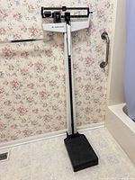 Full view of Health o meter mechanical physician beam scale in bathroom setting, showing base, column, balance beam, and height rod