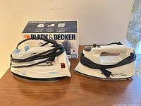 Both steam irons side by side, showing cords and box