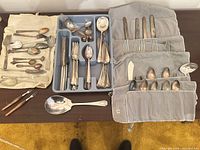 Overall view of all flatware pieces laid out with two roll cases and tray