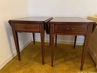 Pair of matching drop-leaf end tables showing overall form, drawers closed, leaves down