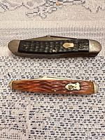Two closed pocket knives, black and brown jigged bone handles