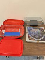 Overall view of two glass baking dishes, red silicone lid, red insulated carrier, boxed 13-inch Snow Flake platter