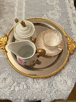Overview of tray holding teacup, saucer, creamer, lidded sugar bowl