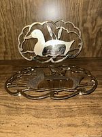 Both silver-tone duck trivets front view