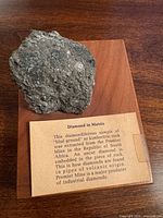 Full view of kimberlite specimen on wood base showing diamond crystal and label text