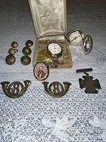 Group view of all items: wristwatch in case, compass, buttons, bugle insignia, medal, portrait pin