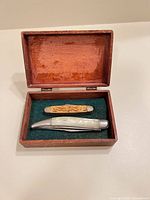 Open wooden box showing both pocket knives inside