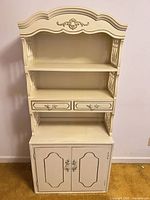 Full view of cream/off-white bookshelf showing open shelves, drawers, and cabinet