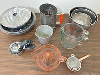 Group shot of entire lot: juicer, Pyrex cup, sifter, measuring cups, mixing bowls, baking pans