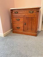 Front view of wooden cabinet showing drawers, door, hardware, marble top