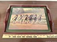 Top view of wooden tray showing horse racing artwork and handles with ruler for scale