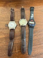 Three wristwatches laid out side by side on wooden surface