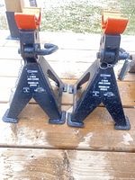 Front view of black Shop Iron jack stand pair showing labels and orange saddles