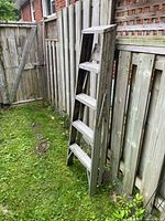 Ladder leaning against fence, side view shows four treads