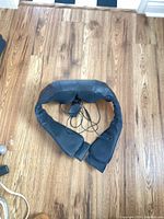 Top view of black neck/shoulder wrap massager showing cord and adapter