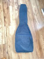 Front view of black nylon electric guitar gig bag showing overall shape and front pocket
