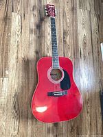 Full front view of Cariboo red dreadnought acoustic guitar showing body, neck, and headstock