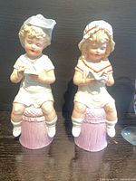 Front view of both porcelain child figurines on pink bases