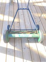 Front view of green Lee Valley manual reel mower on wooden deck