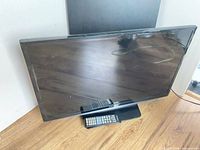 Front view of Samsung 28" TV on stand with remote placed on base