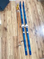 Full view of skis and poles on wood floor