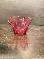 Angled view of cranberry glass dish showing ruffled rim and colour