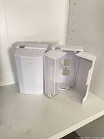 Three white plastic protective outlet covers standing open and closed