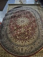 Full view of oval area rug showing red and beige floral medallion pattern