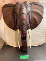 Full view of carved wooden elephant head wall decor with tusks