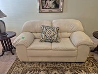 Front view of off-white leather loveseat with cushion