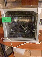 Front view of Ronco rotisserie oven showing glass door, power cord and interior accessories