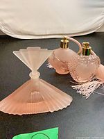 Three pink glass perfume bottles: fan-stopper, round atomizer with hose, heart-pattern atomizer