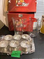Complete lot showing boxed set, six wrapped cups on tray, scoop, tongs, and glass pitcher