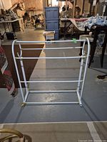 Front view of white metal quilt stand showing four rails and brass-tone accents