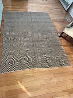 Full view of brown and white geometric woven bedspread laid out on floor
