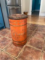 Full view of orange metal flour bin showing stencilled "Flour" text and decorative band