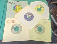 Five 7" vinyl records with sleeves spread on table