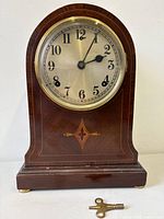 Front view of inlaid wood mantel clock with key