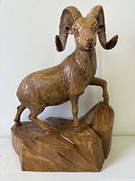 Front view of carved mountain goat on rock base