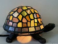 Lamp lit, showing multicolored stained glass shell and metal limbs