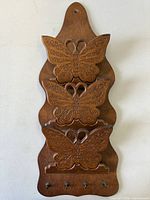 Front view showing full mail holder with butterfly carvings and peg hooks