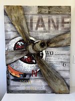 Full view of mixed-media propeller artwork on wood panel