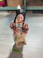 Front view of Danbury Mint Native American porcelain doll on stand