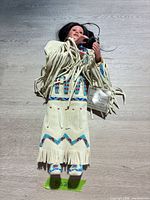 Full view of porcelain Native American doll in buckskin dress