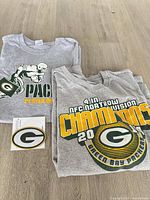 Two folded Packers T-shirts and packaged logo patch