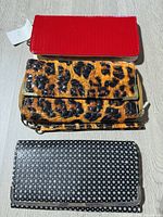 Three wallets laid out: red faux-croc, leopard print, black studded