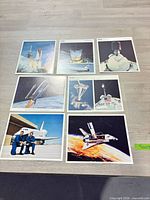 Seven NASA shuttle lithographs arranged on table